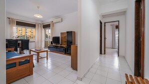 A modern living room with a sofa, TV, and dining area. - Apartment 'T2 Premium' with Shared Pool, Wi-Fi and Air Conditioning (Portimão)