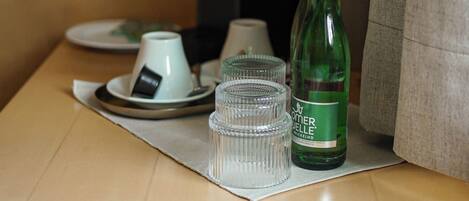 A table with a bottle, glasses, a cup, and a menu.