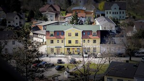 A multi-story building with a green roof, surrounded by residential houses. - Hotel Zur Alten Schule (Pitten)
