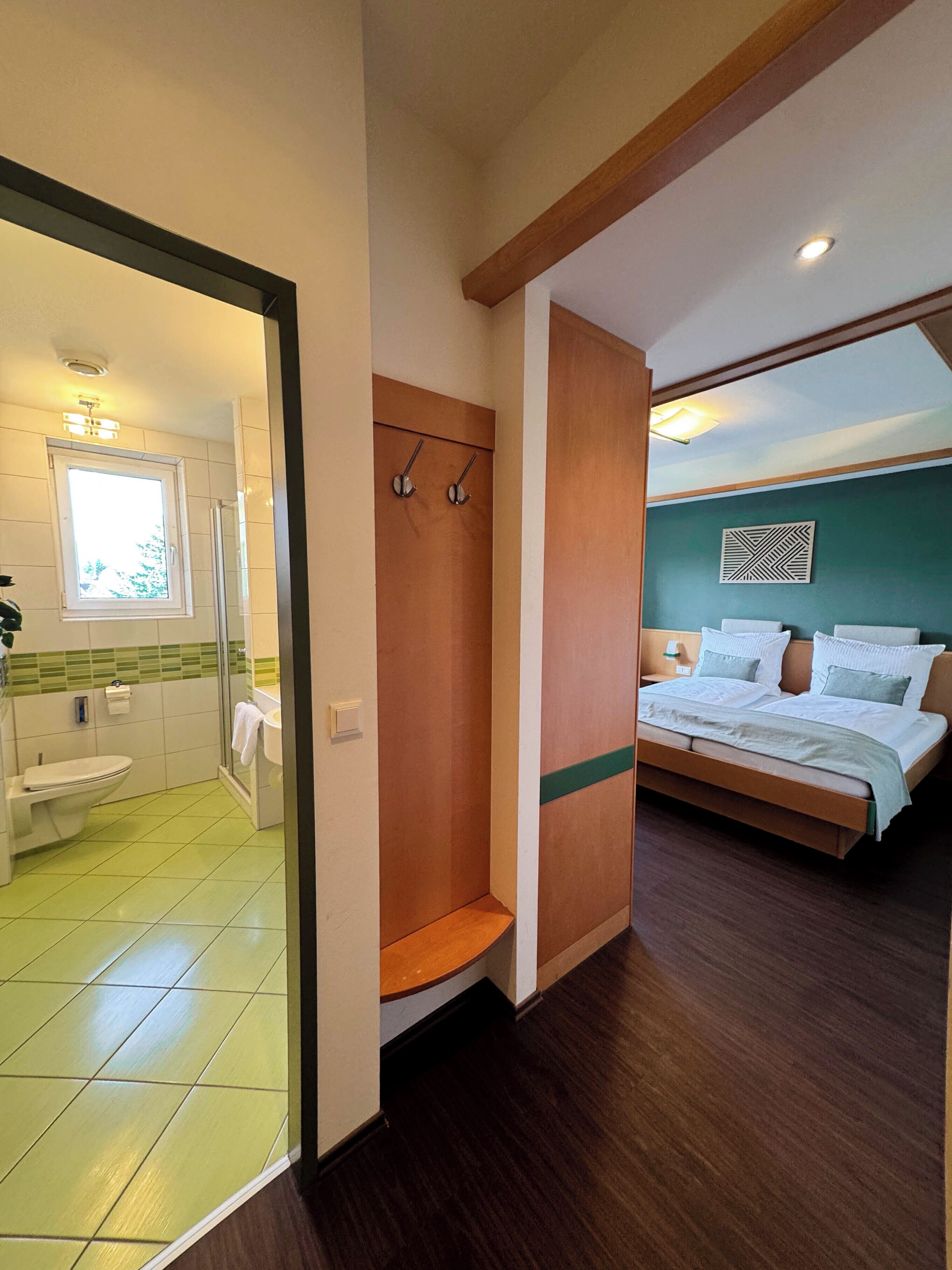 Een hotelkamer met een badkamer, douche, bed en uitzicht.