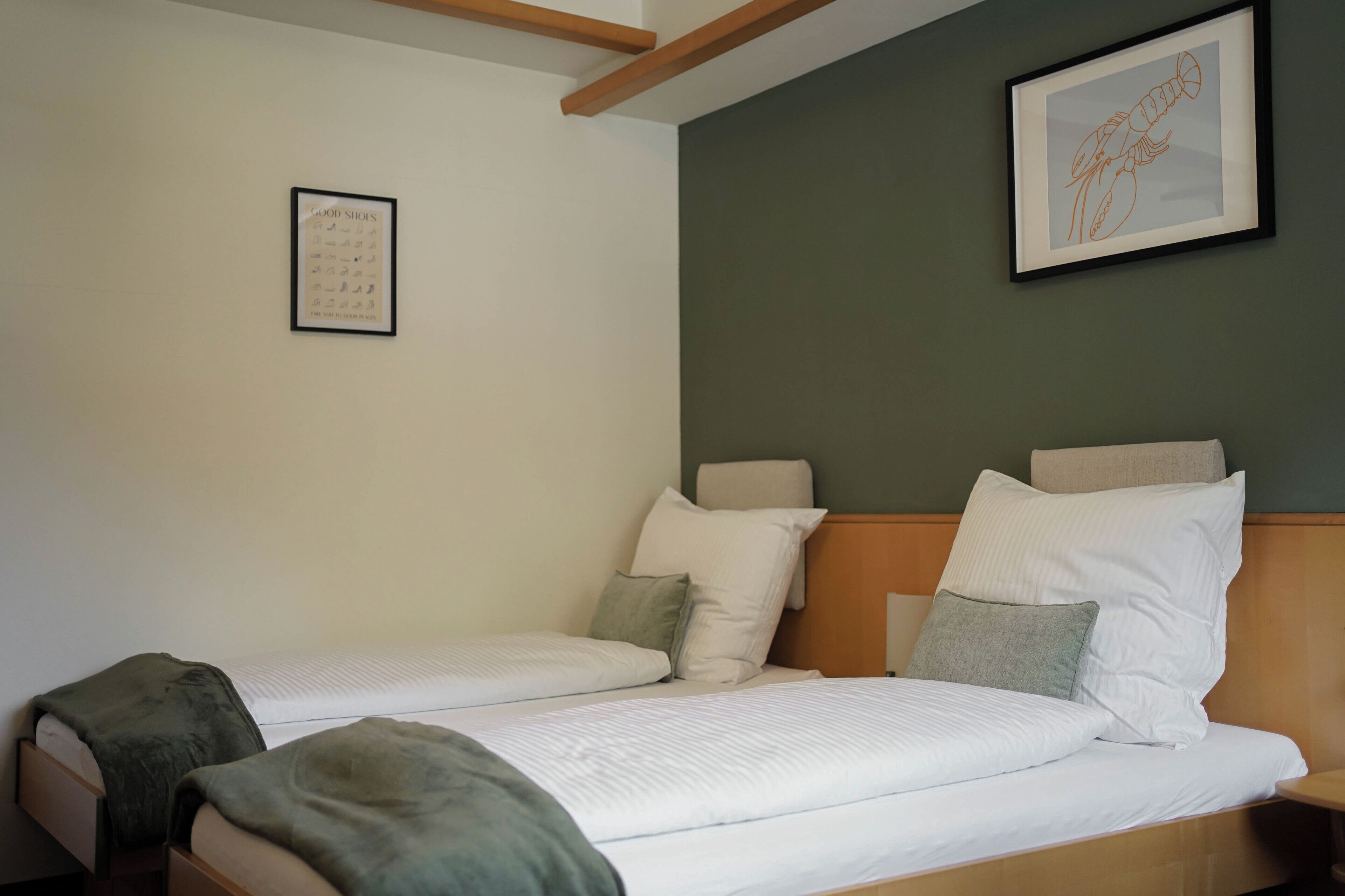 Una habitación de hotel con dos camas individuales, un cuadro en la pared y una mesita.