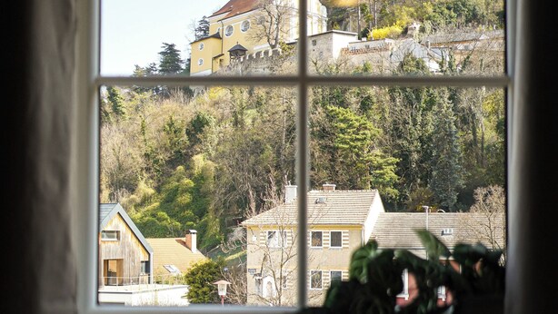 A window with a view of a building and trees. - Hotel Zur Alten Schule (Pitten)