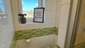 A bathroom with a window, a framed quote, a potted plant, and a toilet.