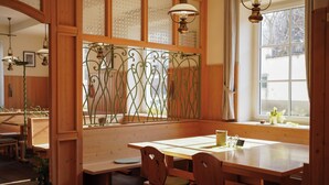 A wooden dining area with a table, chairs, and a decorative metal partition. - Hotel Zur Alten Schule (Pitten)