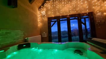 Une pièce dotée d’un jacuzzi, d’un plafond en bois et offrant une vue à travers de grandes portes vitrées.