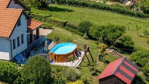 Um imóvel residencial com piscina, varanda coberta e vinhedo ao fundo.