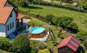Ein Wohnhaus mit Swimmingpool, überdachter Terrasse und einem Weinberg im Hintergrund.