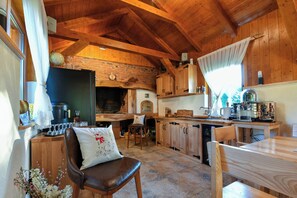A rustic kitchen with wooden beams, a brick wall, and a coffee machine.