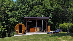 A wooden cabin with a covered porch, a sauna, and outdoor seating.