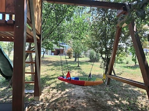 A wooden swing set with a hammock seat, a ladder, and a view of a building in the background. - Charming home with pool and jacuzzi amid vineyards near Kloštar Ivanić. (Kloštar Ivanić)