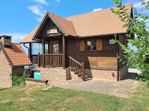A wooden cabin with a sloped roof, a wooden porch, and a brick chimney. - Charming home with pool and jacuzzi amid vineyards near Kloštar Ivanić. (Kloštar Ivanić)