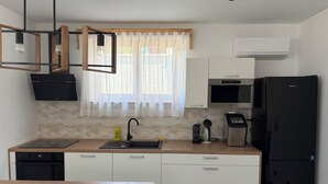 Een moderne keuken met een houten aanrecht, een zwarte koelkast, een magnetron, een koffiezetapparaat en een spoelbak met een zwarte kraan.