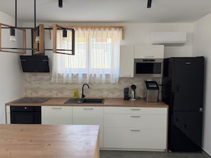 A modern kitchen with a wooden countertop, a black refrigerator, a microwave, a coffee maker, and a sink with a black faucet. - Modern villa with pool, jacuzzi, and sauna for family relaxation in Bilogora. (Maglenča)