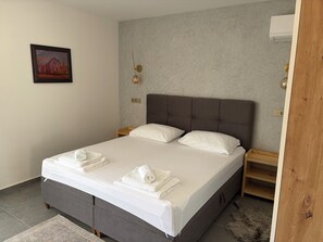 A neatly made bed with pillows and folded towels, a headboard, bedside tables, and a painting on the wall. - Modern villa with pool, jacuzzi, and sauna for family relaxation in Bilogora. (Maglenča)