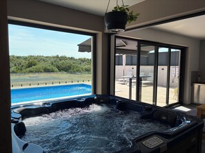 Boblebad med udsigt til en swimmingpool og en terrasse med udendørs møbler.