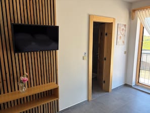 A room with a mounted flat-screen TV, a wooden slat wall, a wooden door, and a tiled floor. - Modern villa with pool, jacuzzi, and sauna for family relaxation in Bilogora. (Maglenča)