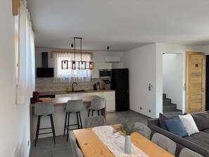 Et moderne køkken med en central ø, barstole og et spisebord med en vase blomster.