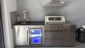 Cocina compacta con horno empotrado, microondas y pileta de acero inoxidable.
