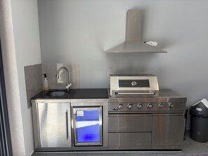 Cocina compacta con horno empotrado, microondas y pileta de acero inoxidable.