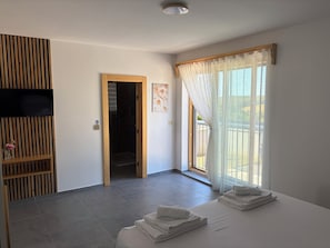 A hotel room with a bed, a TV, a shower, and a view of the outdoors. - Modern villa with pool, jacuzzi, and sauna for relaxation and family getaway. (Maglenča)