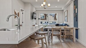 Una cocina moderna con una isla grande, sillas de madera y vistas al exterior.