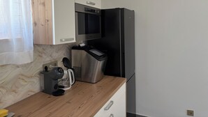 Eine Küche mit Backofen, Kaffeemaschine und Kühlschrank.