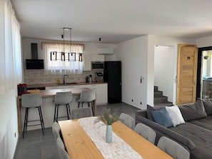 A modern kitchen with a dining area, a sofa, and a staircase leading to another level. - Modern villa with pool, jacuzzi, and sauna in Bilogora for family relaxation. (Maglenča)