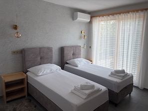 A hotel room with two beds, a wooden nightstand, a fur rug, and a window with sheer curtains. - Modern villa with pool, jacuzzi, and sauna in Bilogora for family relaxation. (Maglenča)