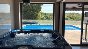 Ein Whirlpool mit Blick auf einen Swimmingpool und einen Garten.