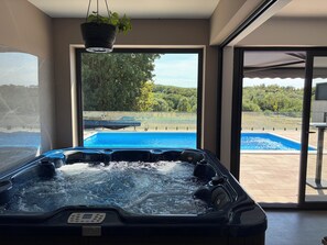 A hot tub with a view of a swimming pool and a garden outside. - Modern villa with pool, jacuzzi, and sauna in Bilogora for family relaxation. (Maglenča)