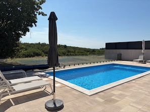 A swimming pool with a clear blue water surface, surrounded by a tiled deck.