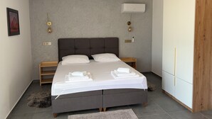 Ein modernes Schlafzimmer mit einem großen Bett, Nachttischlampen, einem Kleiderschrank und einer Decken-Klimaanlage.