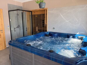 A spa area with a hot tub, a shower enclosure, and a wooden door. - Modern villa with pool, jacuzzi, and sauna in Bilogora for relaxing getaway. (Maglenča)