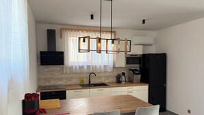 Eine moderne Küche mit einer Holzinsel, Barhocker, einem eingebauten Ofen und einem schwarzen Kühlschrank.