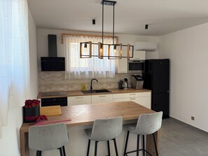 A modern kitchen with a wooden island, bar stools, a built-in oven, and a black refrigerator. - Modern villa with pool, jacuzzi, and sauna in Bilogora for relaxing getaway. (Maglenča)