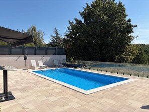 A rectangular swimming pool with a tiled deck, two white lounge chairs, and a black umbrella. - Modern villa with pool, jacuzzi, and sauna in Bilogora for relaxing getaway. (Maglenča)