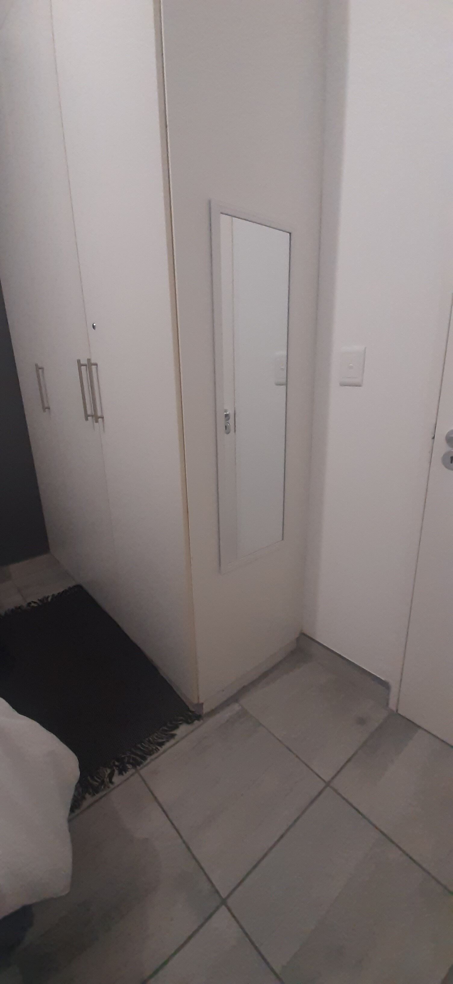 Una habitación con un armario, una cama y una alfombra pequeña.