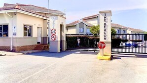 A gated entrance to a residential area with a stop sign and a no parking sign.