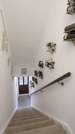 A staircase with a handrail, a wall-mounted shoe rack, and a door at the bottom. - The Lily  Suite with parking (Berkshire)