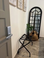 Un pasillo con un banco de metal negro, una planta en maceta y un espejo grande con marco negro.