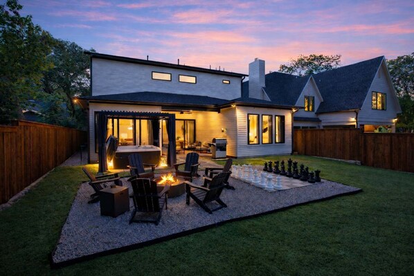 A modern house with a backyard patio, outdoor seating, and a fire pit. - 6BD/5BA of Modern Elegance | Cinema, Games, HotTub (Dallas)