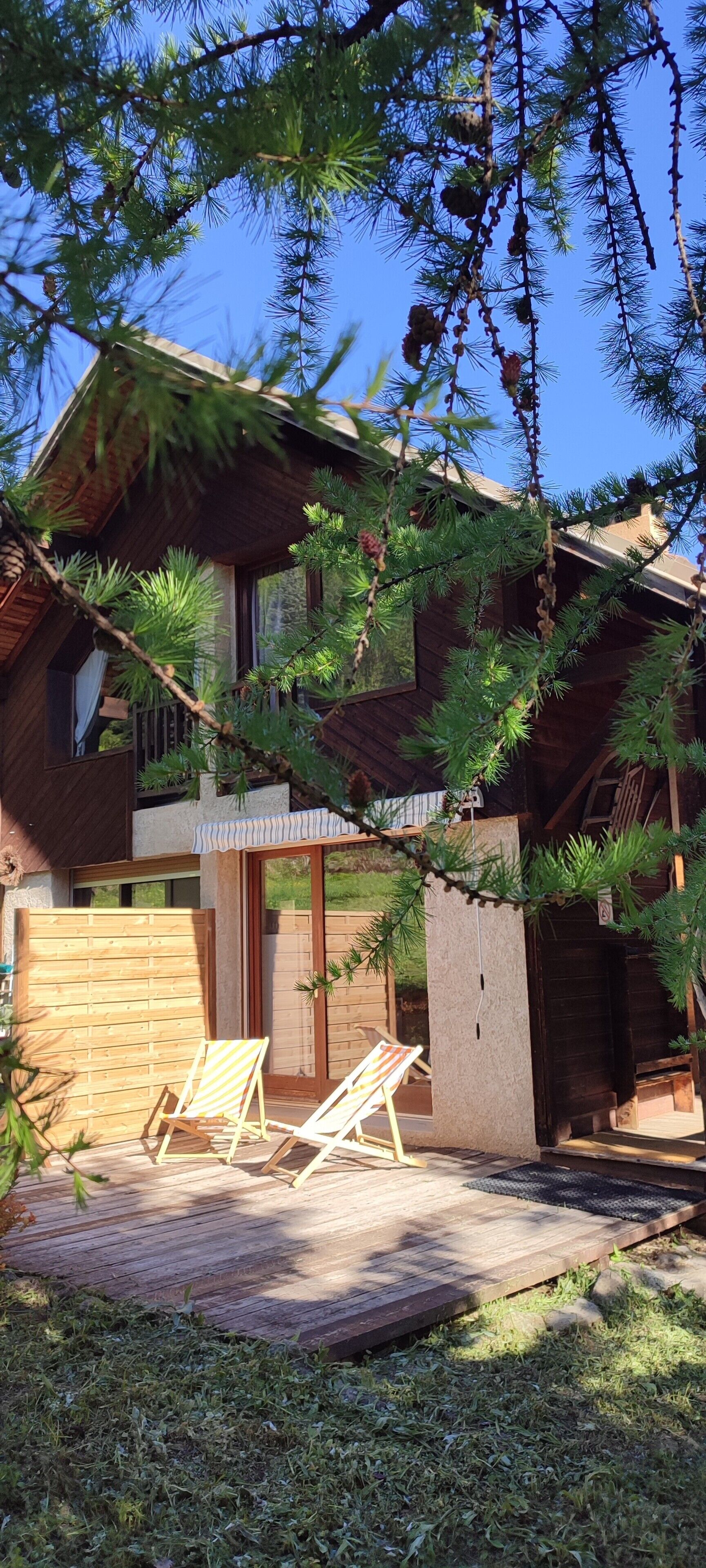 Ein Holzhaus mit Veranda, zwei Stühlen und einer kleinen Terrasse.