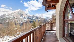 A wooden balcony with a view of snow-covered mountains.