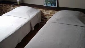 A room with two beds, a stone wall, a picture on the wall, and a small table with a lamp. - Holiday Home 'Gîte Joly' with Private Terrace, Private Garden and Wi-Fi (Corseul)