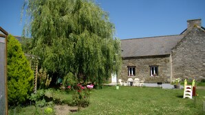 A stone building with a garden in front, a wooden fence, and a tree. - Holiday Home 'Gîte Joly' with Private Terrace, Private Garden and Wi-Fi (Corseul)