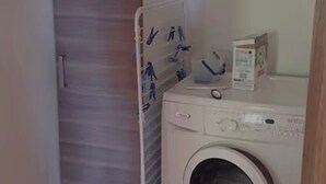 A laundry area with a washing machine, a drying rack, and a door with a sign. - Holiday Home 'Gîte Joly' with Private Terrace, Private Garden and Wi-Fi (Corseul)