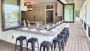 Een moderne keuken met een lang eiland aanrecht, barstoelen en uitzicht op de achtertuin.
