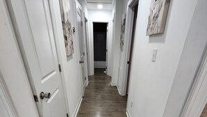 A hallway with white walls, wooden flooring, and doors leading to rooms. - 3-bedroom  house in welcoming Garner with cool BAMBOO for relaxing stays (Garner)