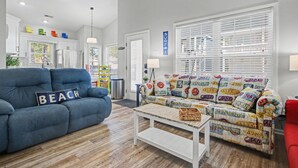 A living room with a blue sofa, a patterned couch, and a coffee table. - The Surf Shack-Limo Golf Cart & Linens Included in Ocean Lakes Family Campground (Myrtle Beach)