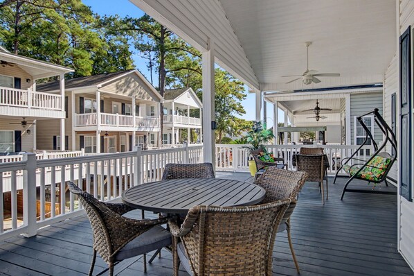 A covered outdoor deck with wicker furniture and a table, surrounded by white railings. - The Surf Shack-Limo Golf Cart & Linens Included in Ocean Lakes Family Campground (Myrtle Beach)